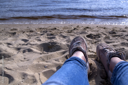 Female legs in sneakers on a sand. Relax on the beach.