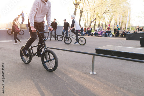 BMX cyclists ride a bike on a skate park. BMX rider on the background of the park and people with bikes. BMX concept.