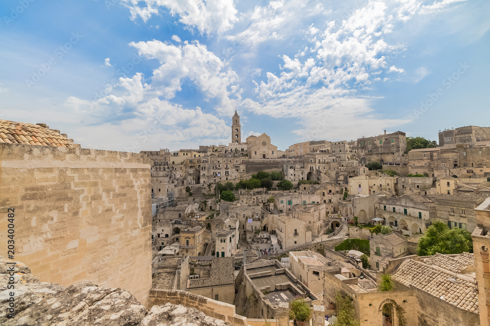 panoramic view of typical stones Sassi di Matera and church of Matera under blue sky with clouds