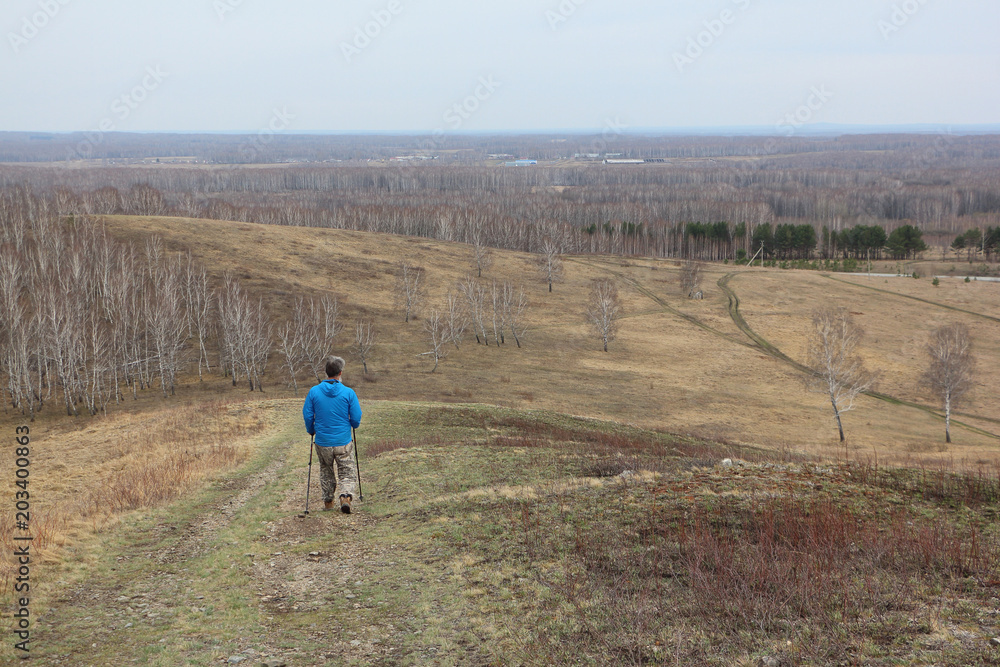 Nordic Walking -  adult man descending from the mountain Big, Bugotaksky hills, Novosibirsk region, Russia