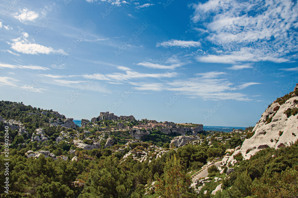 Panoramic view of the village and ruins of the Baux-de-Provence Castle on top of cliff and sunny blue sky. Bouches-du-Rhone department, Provence-Alpes-Côte d'Azur region, southeastern France