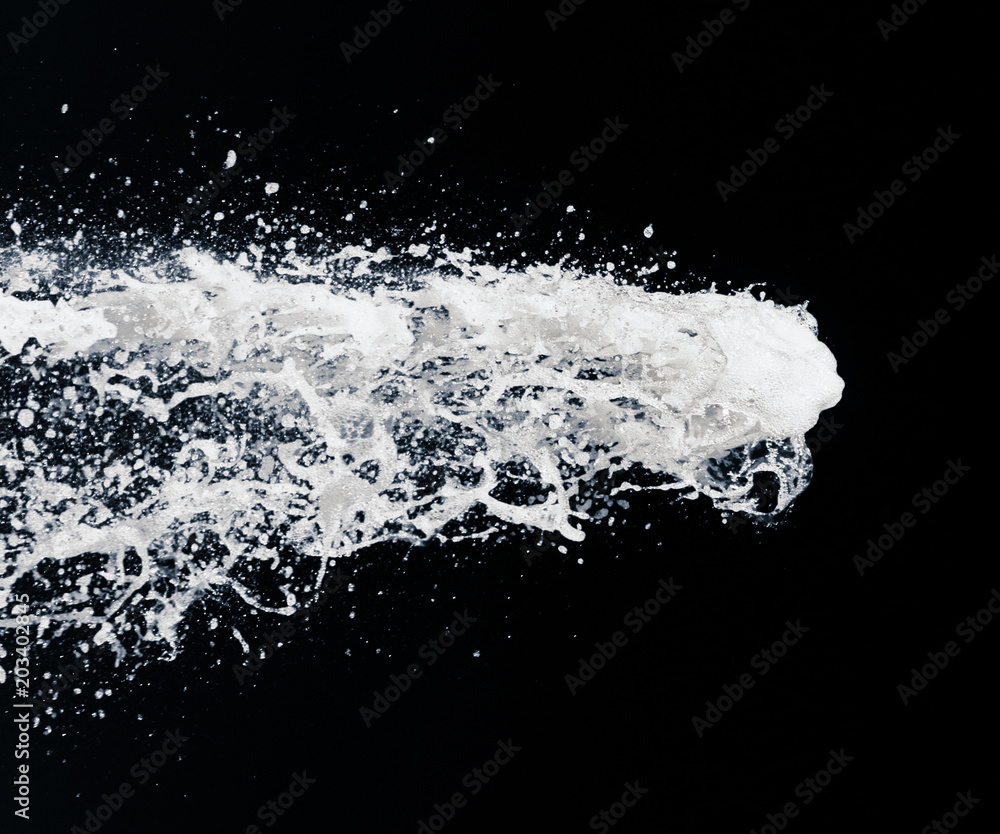 a jet of foam from a bottle of champagne on a black background. festive image