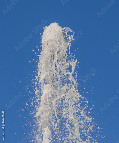 a strong current of pure cold water gushes up under a lot of pressure on the background of blue sky