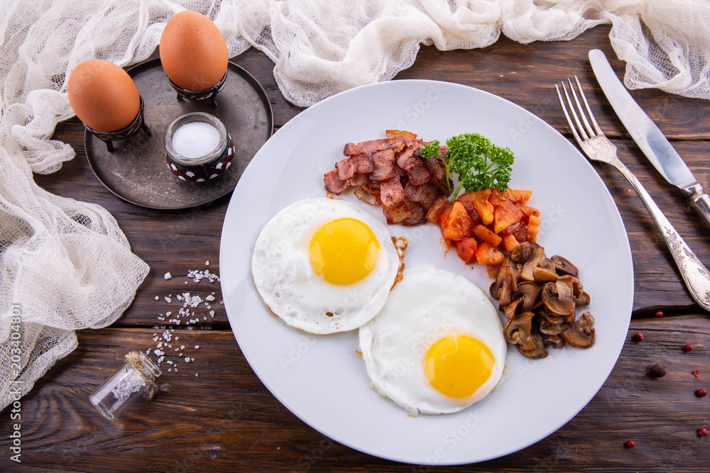 A breakfast from fried eggs with bacon and tomatoes, champignons and greens
A breakfast from fried eggs with bacon and tomatoes, champignons and greens