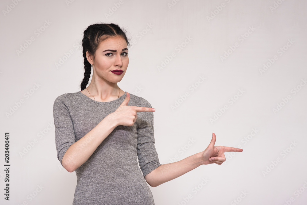 Portrait of a beautiful brunette girl on a white background showing hands to the side. Portrait of a beautiful brunette girl on a white background showing hands to the side.