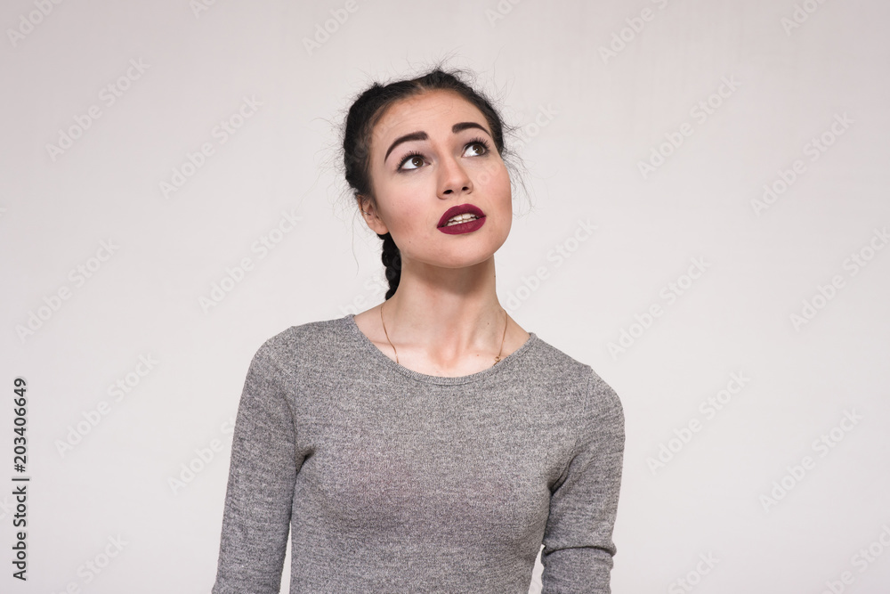 Portrait of a beautiful brunette girl on a gray background showing her emotions Portrait of a beautiful brunette girl on a gray background showing her emotions