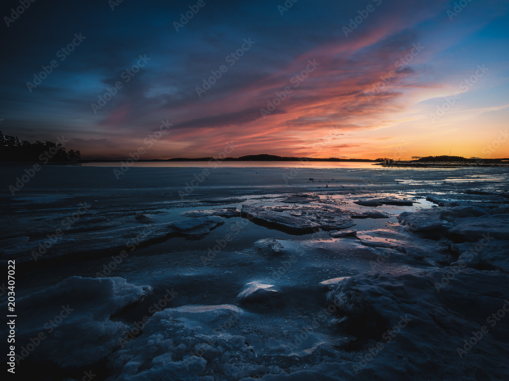 Frozen sea against colorful sunset in Ruissalo, Turku, Finland