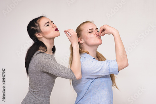 Portraits on the gray background of two girls girlfriends showing emotions.