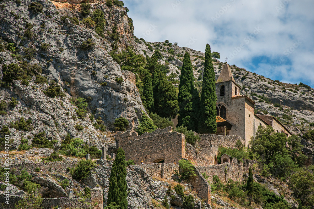 View of the Notre-Dame de Beauvoir church amidst cliffs and rock stairway, above the graceful Moustiers-Sainte-Marie village. Alpes-de-Haute-Provence department, Provence region, southeastern France