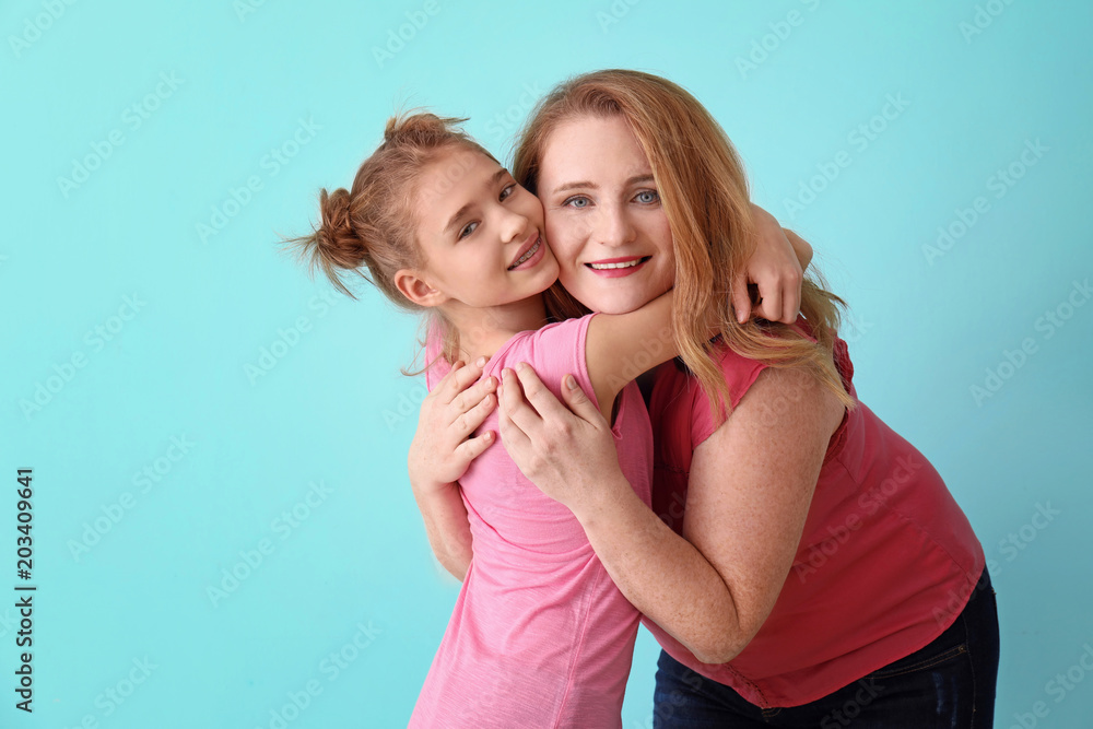 Happy mother and daughter hugging on color background Happy mother and daughter hugging on color background