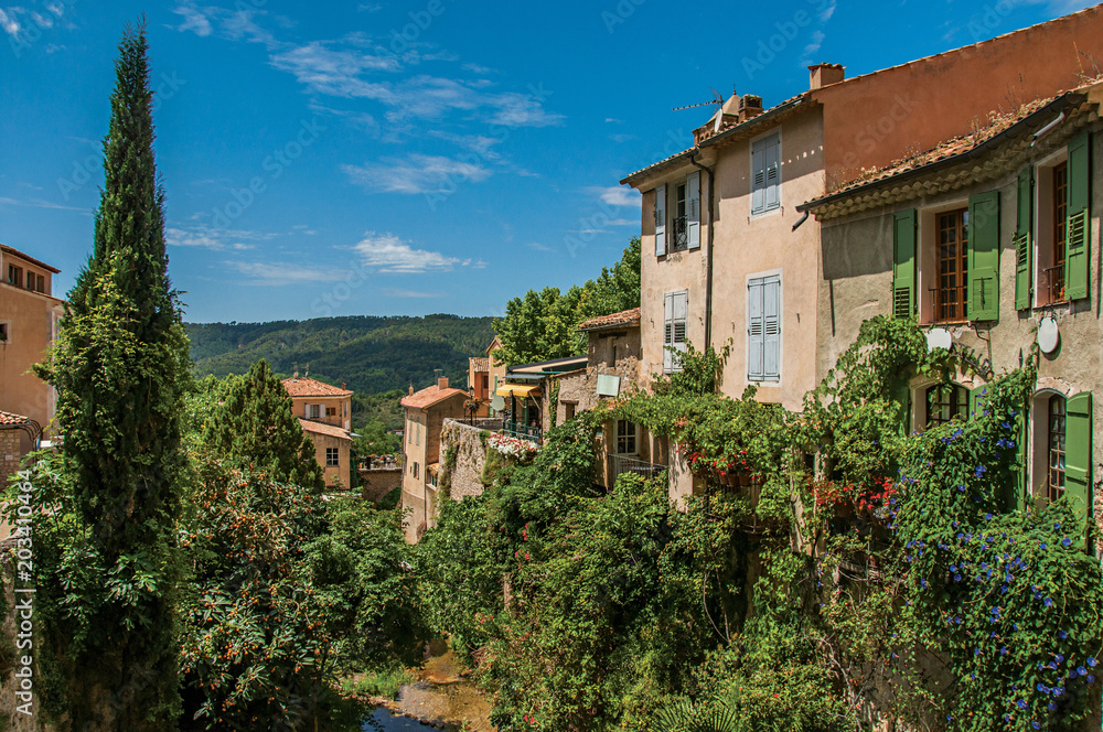 View of houses near creek and bluff with vegetation in the charming village of Moustiers-Sainte-Marie. In the Alpes-de-Haute-Provence department, Provence region, southeastern France