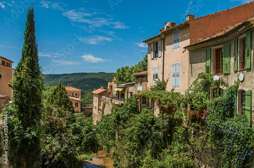 View of houses near creek and bluff with vegetation in the charming village of Moustiers-Sainte-Marie. In the Alpes-de-Haute-Provence department, Provence region, southeastern France