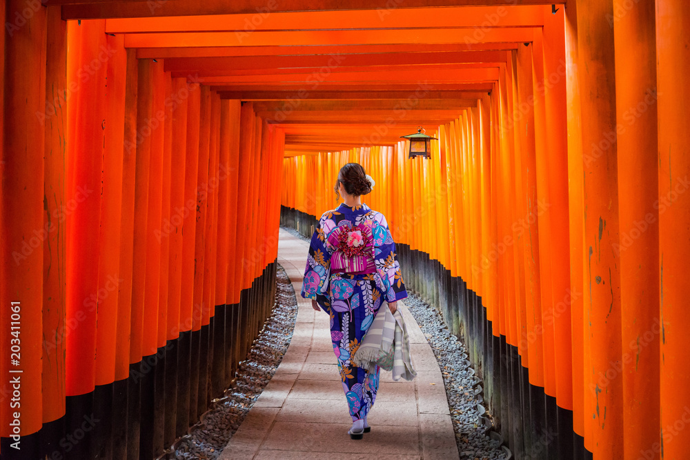 Naklejka premium Kobieta w tradycyjnym kimonie chodzi przy torii bramami, Japonia