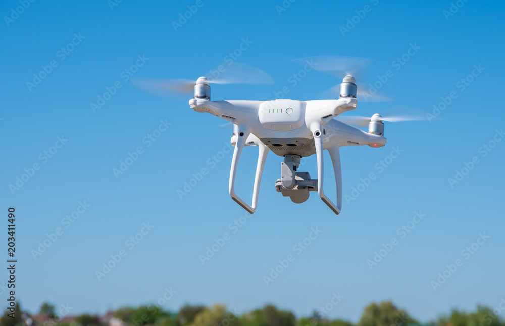 The modern drone, quadrocopter is in the air against the background of the sky and grass The modern drone, quadrocopter is in the air against the background of the sky and grass