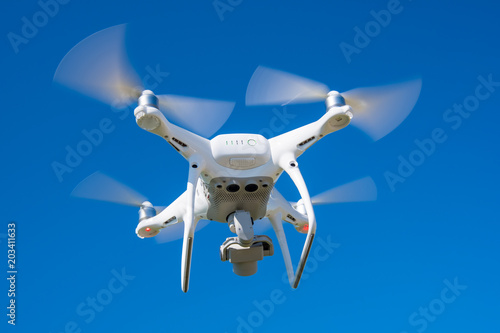 The modern drone, quadrocopter is in the air against the background of the sky and grass