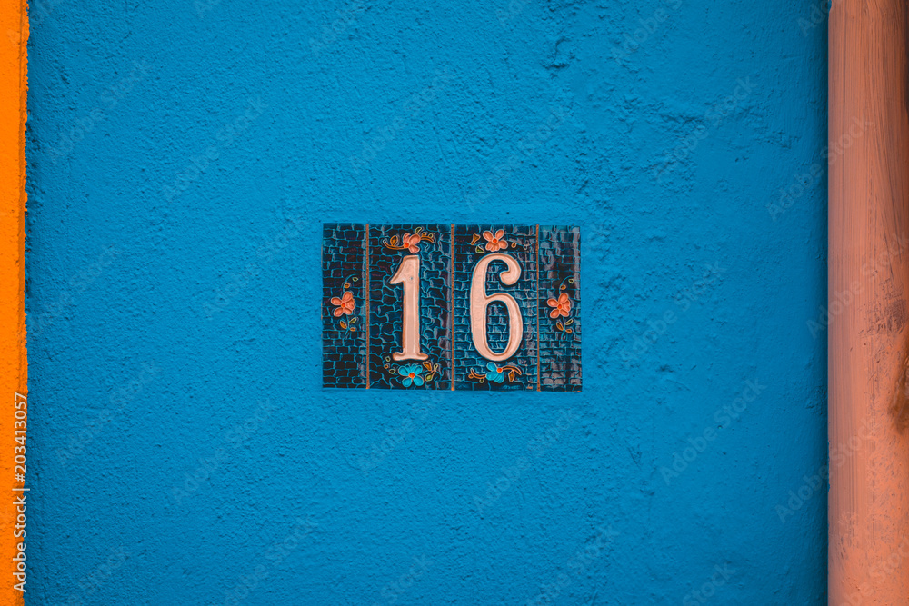 detailed number 16 door sign on blue facade detailed number 16 door sign on blue facade
