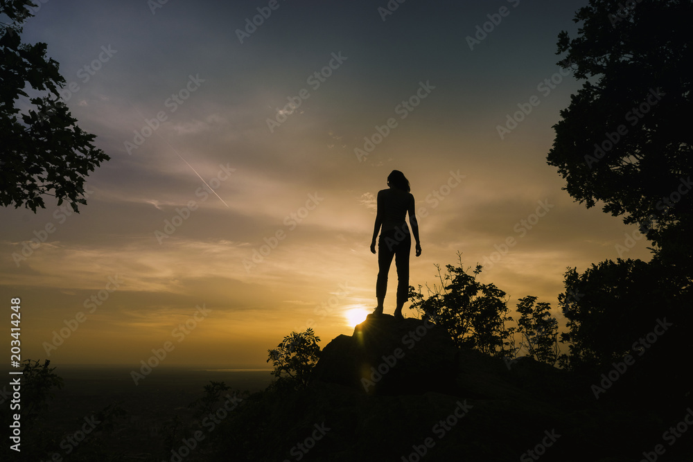 Young girl observing sunset on the top of the mountain.