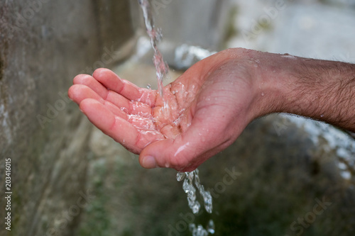 Male hand collecting water from a fountain. Fresh water from a pond