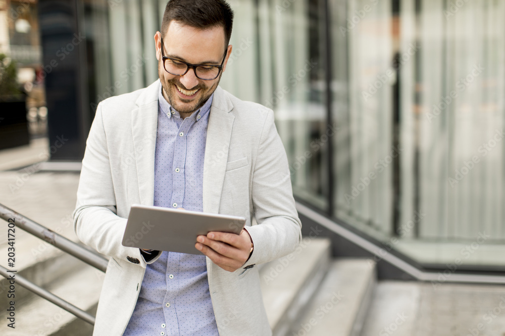 Young businessman with digital tablet by the office building Young businessman with digital tablet by the office building