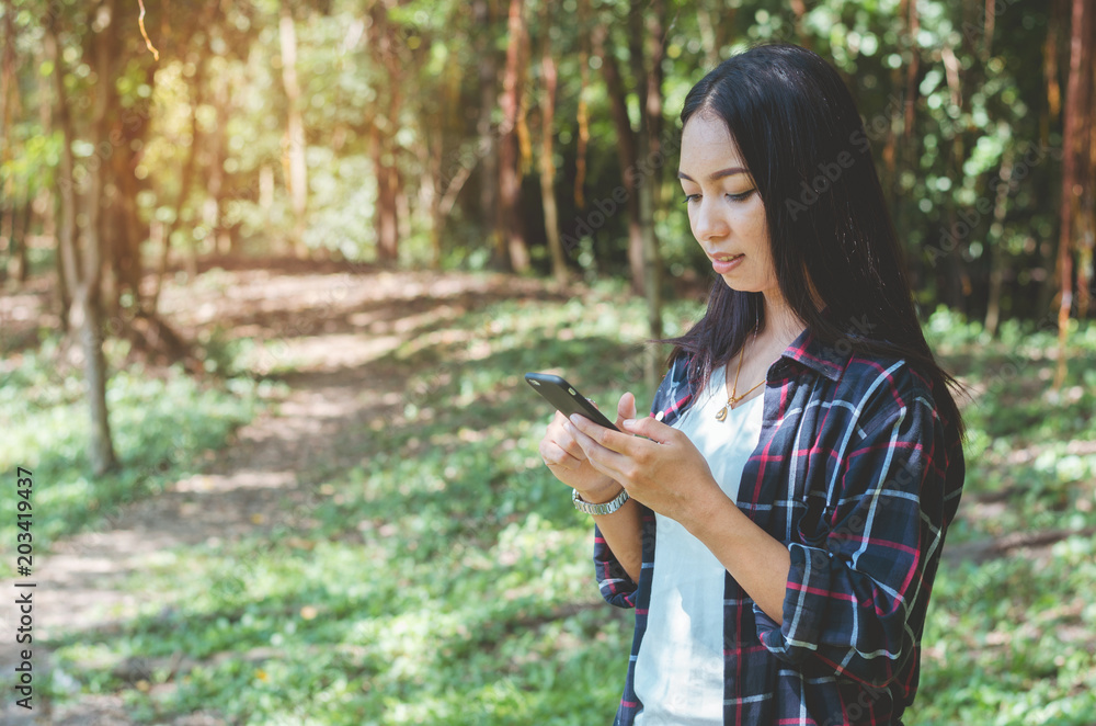 traveler woman using touching on mobile phone ready start to walking on forest way go to hiking travel camping. holiday adventure trekking travel concept. traveler woman using touching on mobile phone ready start to walking on forest way go to hiking travel camping. holiday adventure trekking travel concept.