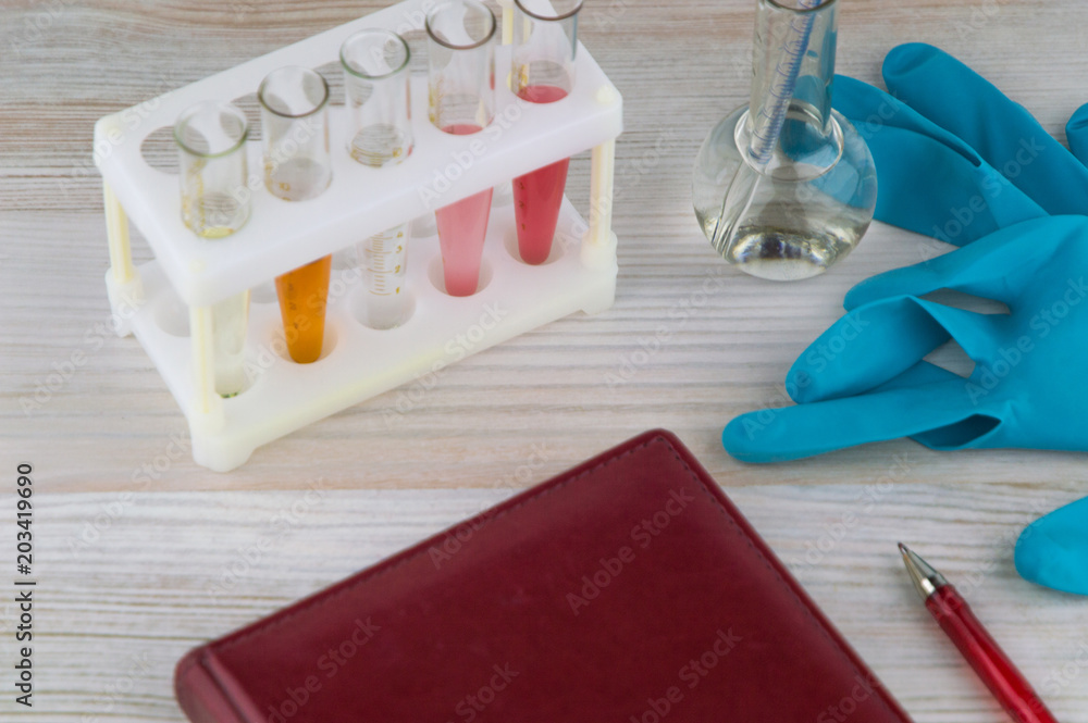 record diagnosis, medical report: the red notebook and red pen on it, around in selective focus, test tube, flask, gauze bandage and gloves of a medical expert around, top view, close