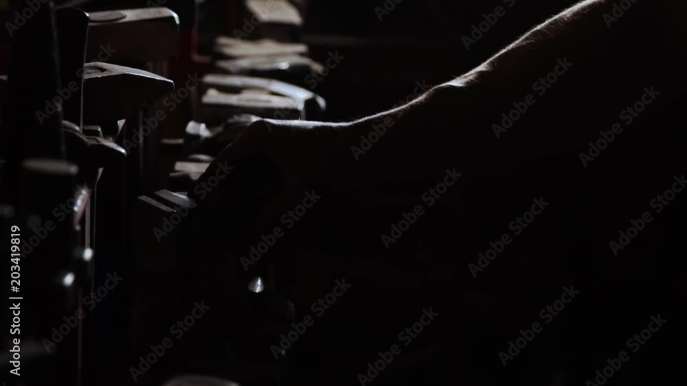 Close-up of a sturdy man's hand takes a metal hammer on a dark background in slow motion. Smith takes his hand hammer for working with metal Close-up of a sturdy man's hand takes a metal hammer on a dark background in slow motion. Smith takes his hand hammer for working with metal