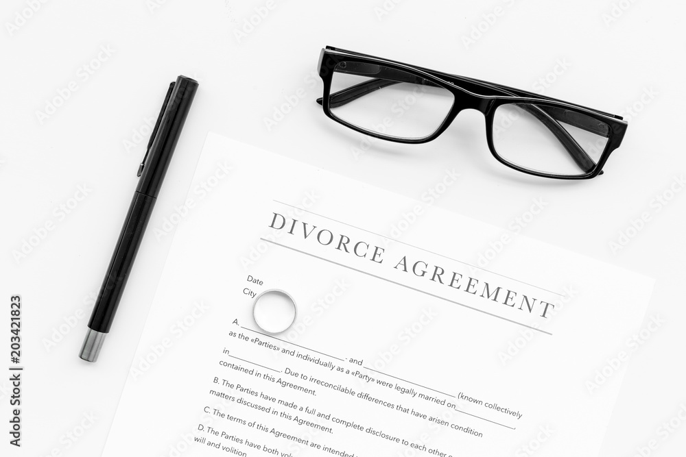 Divorce agreement. Wedding ring on document on white background top view Divorce agreement. Wedding ring on document on white background top view