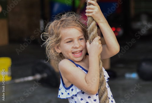 Lachendes Kind spielt auf dem Spielplatz und klettert ein Seil hoch