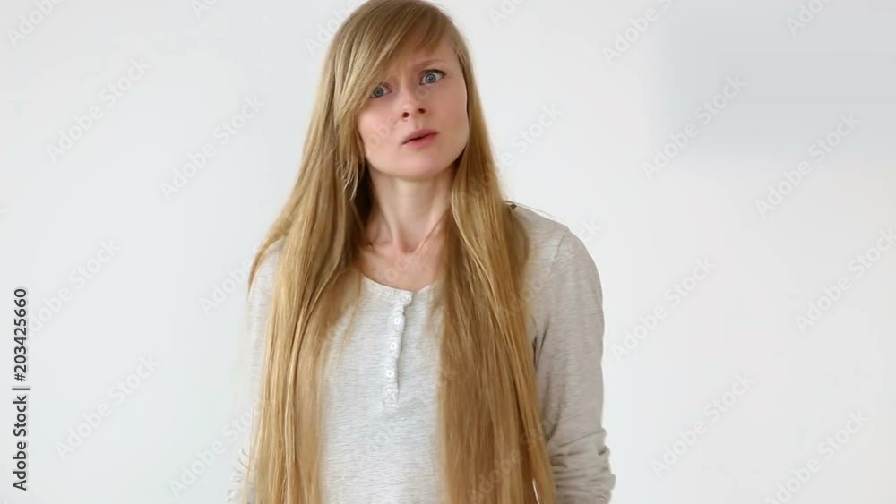 beautiful long-haired girl of European appearance with blond hair posing against white wall. emotions - denial and anger, disagree beautiful long-haired girl of European appearance with blond hair posing against white wall. emotions - denial and anger, disagree