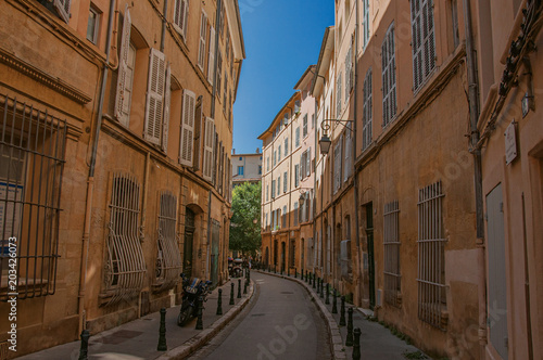 Narrow alley with tall buildings in the shadow in Aix-en-Provence, a pleasant and lively town in the French countryside. Located in Bouches-du-Rhone department, Provence region, southeastern France