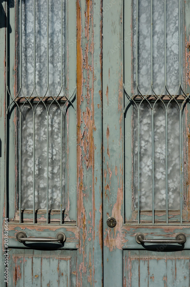 Part of old green faded door with cracked paint. Vintage background, texture.