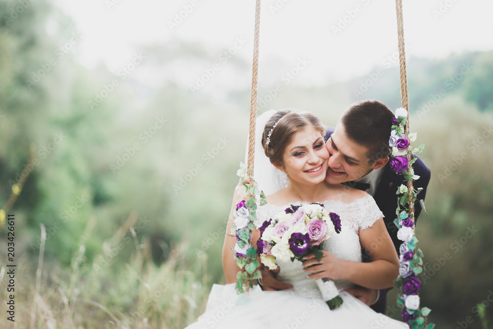 Romantic, fairytale, happy newlywed couple hugging and kissing in a park, trees in background Romantic, fairytale, happy newlywed couple hugging and kissing in a park, trees in background
