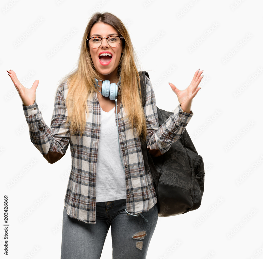 Young student woman with headphones and backpack happy and surprised cheering expressing wow gesture Young student woman with headphones and backpack happy and surprised cheering expressing wow gesture