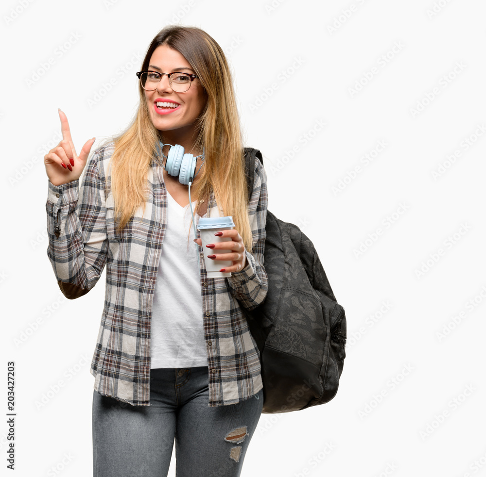 Young student woman with headphones and backpack pointing away side with finger Young student woman with headphones and backpack pointing away side with finger