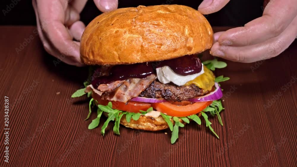 Burger is cooking on black background. Very luscious air bun and marbled beef. Restaurant where each burgers is cooked by hand. Finished burger. Put bun on top. Not made ideal. Not conveyor. Looks Burger is cooking on black background. Very luscious air bun and marbled beef. Restaurant where each burgers is cooked by hand. Finished burger. Put bun on top. Not made ideal. Not conveyor. Looks