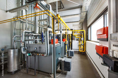The interior of an industrial boiler house with a multitude of pipes, boilers and sensors