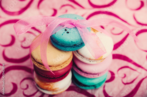 Tasty different colored macarons on pink background 