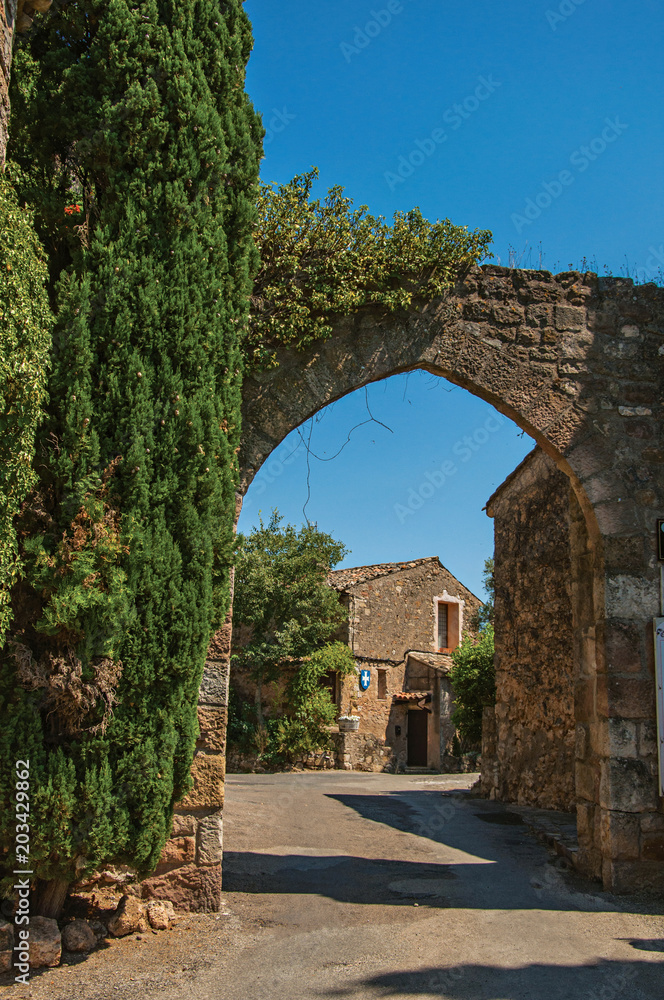 View of stone wall and arch under sunny blue sky at the entrance of the lovely Les Arcs-sur-Argens hamlet, in the way to Draguignan. Located in the Provence region, Var department, southeastern France