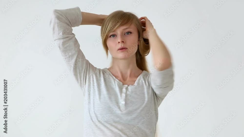 beautiful long-haired girl of European appearance with blond hair making different hairstyles over white background beautiful long-haired girl of European appearance with blond hair making different hairstyles over white background