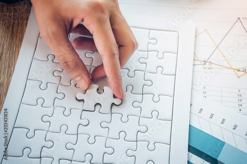 Close up of hands business women piece jigsaw puzzle on coming down into place. Teamwork workplace success and strategy concept.