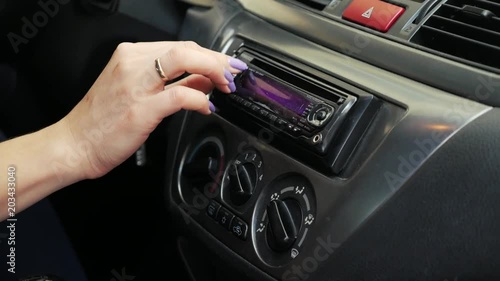 A woman driver adjusts the radio in the car