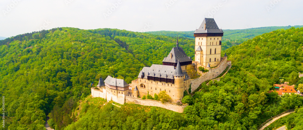 Aerial view to The Karlstejn castle. Royal palace founded King Charles IV. Amazing gothic monument in Czech Republic, Europe. Aerial view to The Karlstejn castle. Royal palace founded King Charles IV. Amazing gothic monument in Czech Republic, Europe.