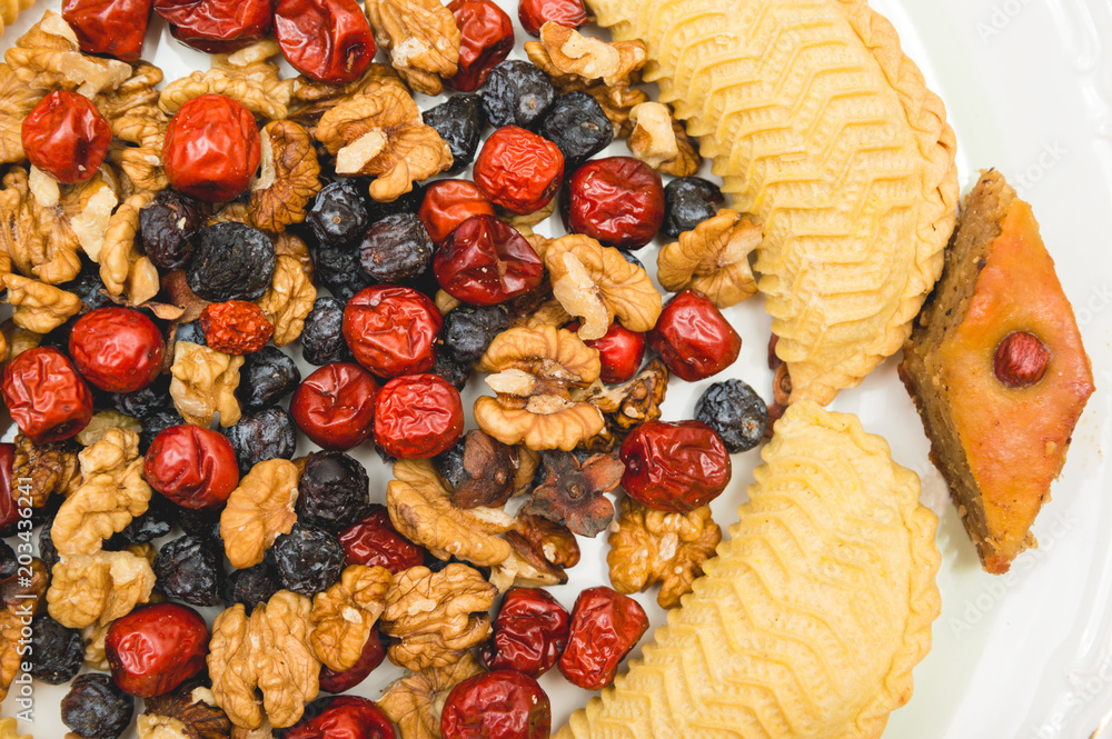 Fototapeta premium Sweets and desserts for the Novruz holiday on plate - shekerbura, baklava, walnuts and dried fruits
