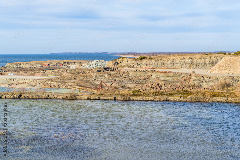 Limestone quarry by the coast on Oland, Sweden. Part of the quarry is waterfilled. Baltic sea in the background.
