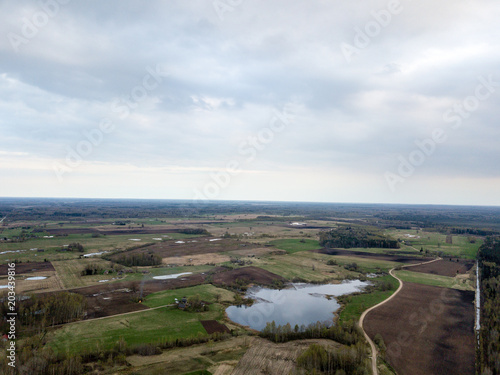 drone image. aerial view of rural area with countryside lake enclosed by fields and forests © Martins Vanags