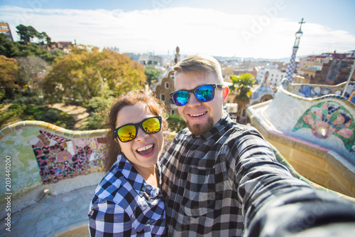 Travel couple happy making selfie portrait with smartphone in Park Guell, Barcelona, Spain. Beautiful young couple looking at camera taking photo with smart phone smiling in love