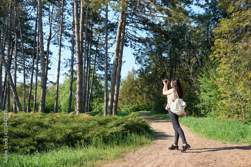 girl with camera taking pictures of nature in spring, beautiful forest and trees on a Sunny day © soleg