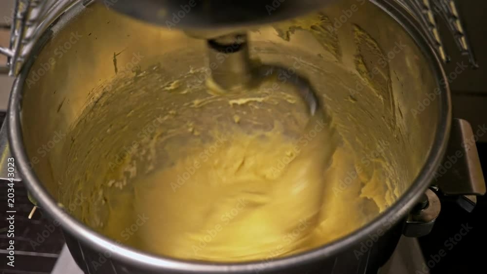 Mixing a dough for bread baking with professional kneader spiral machine at the manufacturing. The dough is kneaded for burgers. Very luscious lush air bun. Mixing a dough for bread baking with professional kneader spiral machine at the manufacturing. The dough is kneaded for burgers. Very luscious lush air bun.