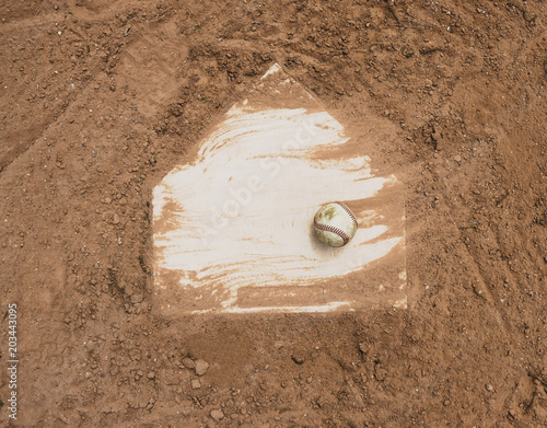 Photography Baseball laying with homeplate on dirt field for game.