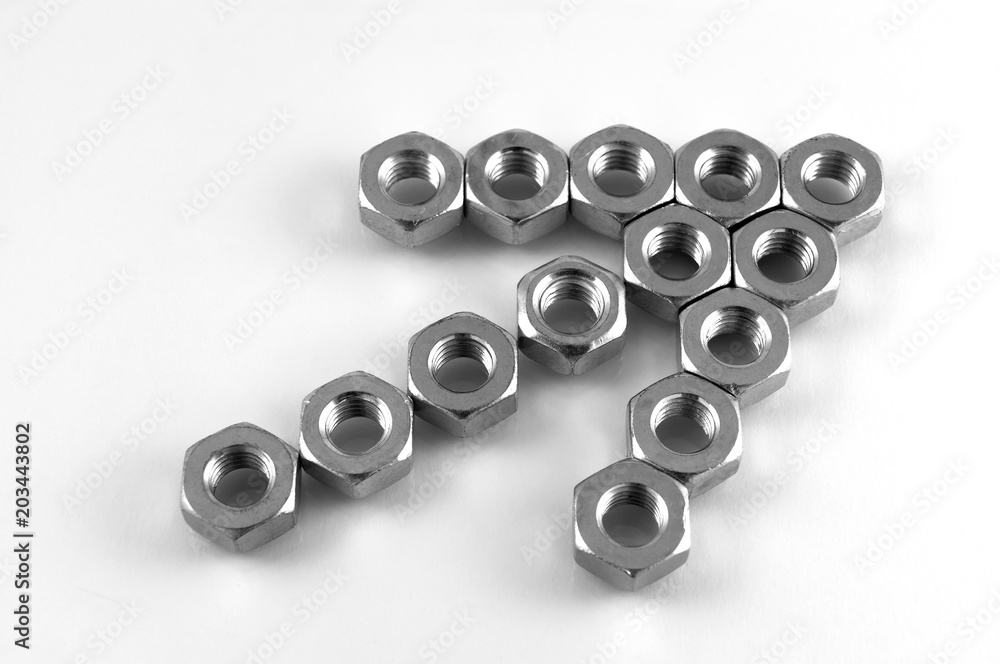 Steel nuts with internal thread, laid in the form of an arrow up and to the right on a white background. Steel nuts with internal thread, laid in the form of an arrow up and to the right on a white background.